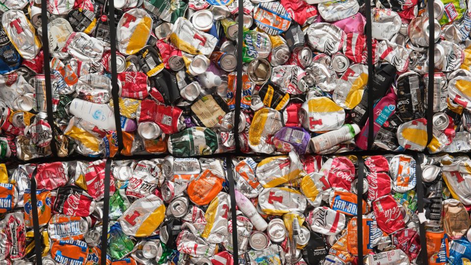 full frame of hundreds of aluminium cans crushed into cubes for recycling. The cans are bring colour with some logos showing 